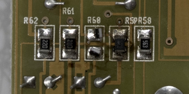 A close-up of a circuit board showing damaged resistors